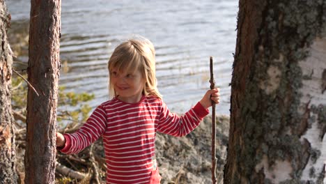 beautiful female child with blonde hair enjoys sunny day in forestry lakeside, handheld view