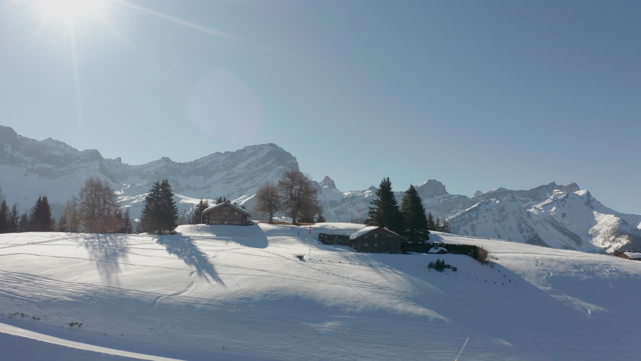Drone che vola verso delle baite su un bellissimo paesaggio innevato.