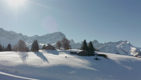 Drone-flying-towards-cabins-on-a-beautiful-snowcovered-landscape