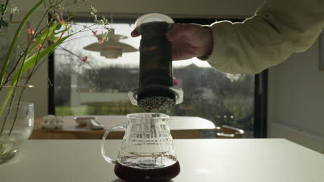 vertiendo café fresco a través de una prensa de vidrio en la luz de la mañana