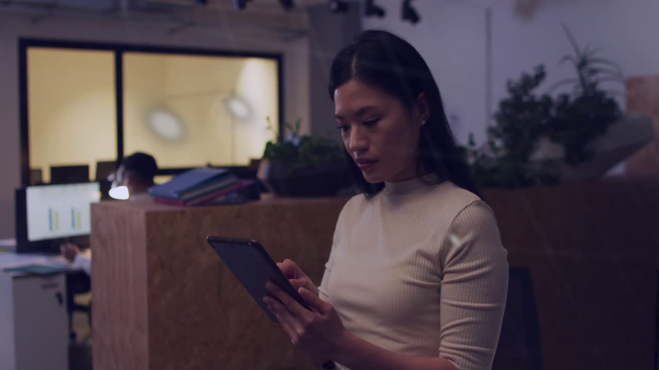 Overlay appearing across tech office, woman scrolling tablet while charts obscuring revealing face