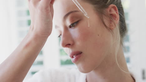 Biracial-woman-applying-face-oil-in-bathroom,-slow-motion