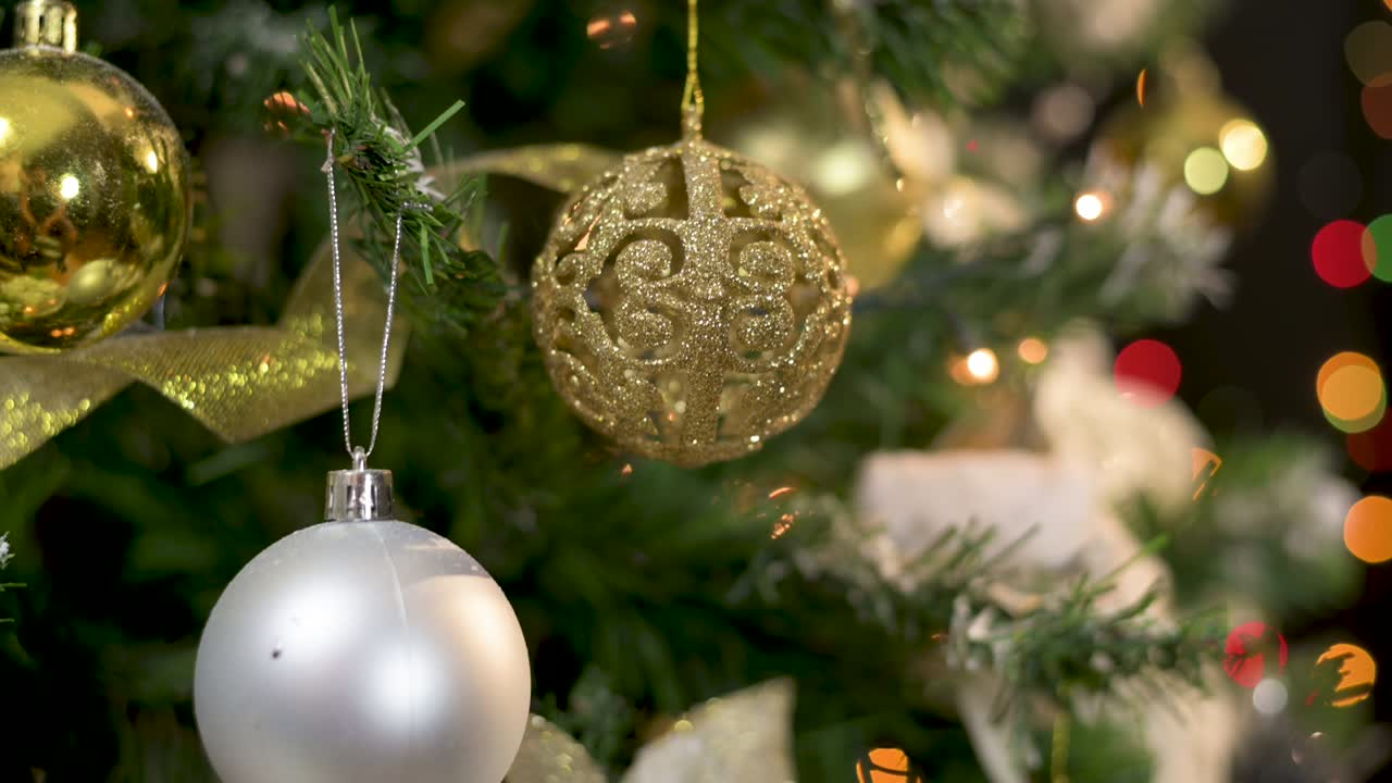 cerca de un hermoso árbol de navidad decorado con adornos dorados, plateados y blancos