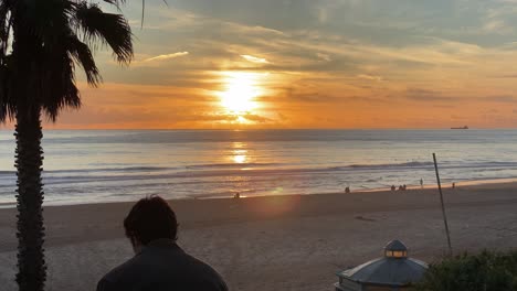 silueta de un joven barbudo en la playa mirando alrededor al atardecer
