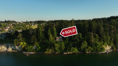 Drone-shot-approaching-a-private-waterfront-cabin-with-a-"SOLD"-sign-above-it