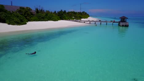 hombre nadando de espaldas en el agua turquesa del mar caribe, imágenes de drones con cielos despejados