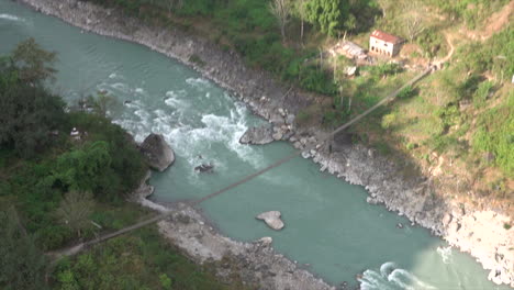 An-aerial-view-of-a-river-and-a-swinging-bridge-crossing-the-river