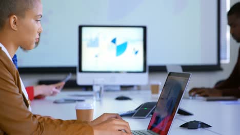 Side-view-of-mixed-race-business-people-working-on-laptop-in-modern-office-4k