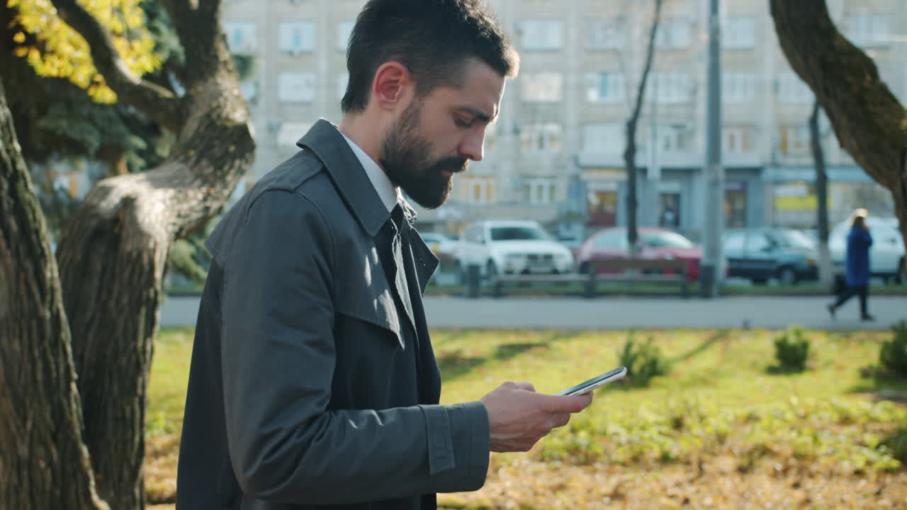 Businessman using smartphone in city park