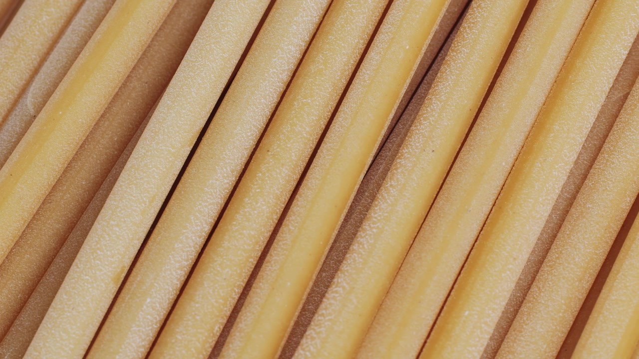 Gros plan de pâtes bucatini crues disposées en diagonale