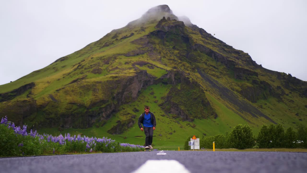 스케이트보더가 아이슬란드에서 아름다운 산을 배경으로 트릭을 합니다.