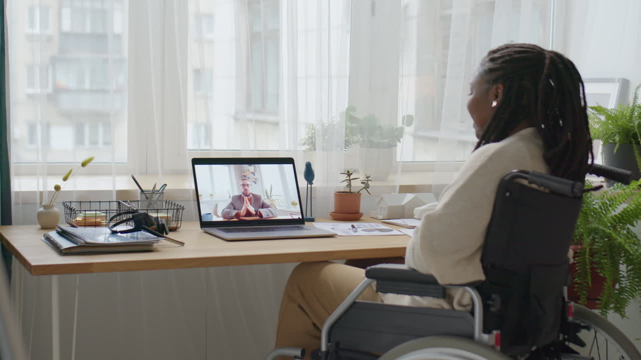 Woman in Wheelchair Video Calling with Colleague At Home