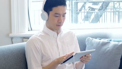 man listening to music on digital tablet in living room 4k