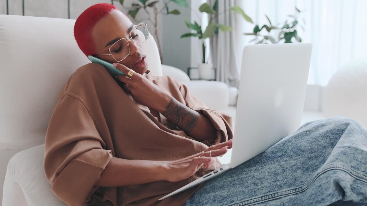 Young busy african american woman speaks on phone and types on laptop