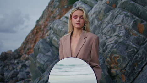 mujer segura modelando playa por la noche. niña de moda de arte sosteniendo espejo redondo