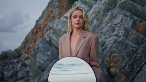 confident woman modeling beach in evening. art fashion girl holding round mirror