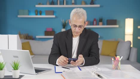 home office worker man gets frustrated while looking at phone.