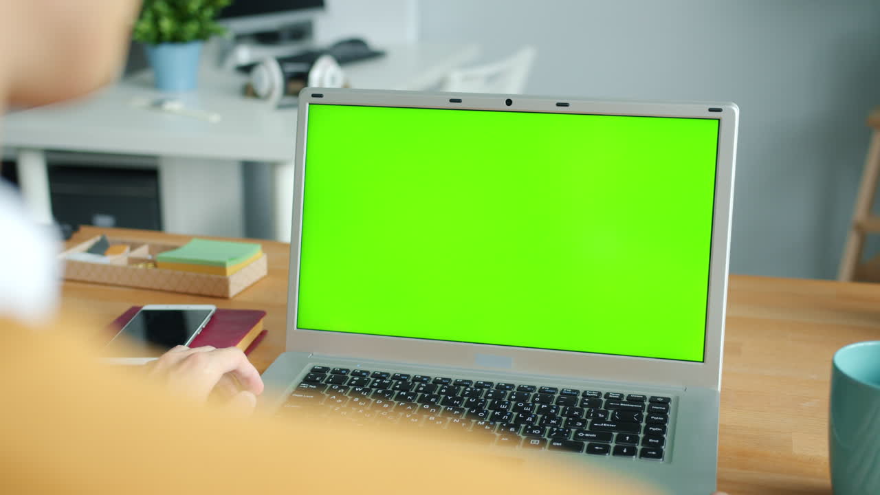 persona trabajando en una computadora portátil con una pantalla verde