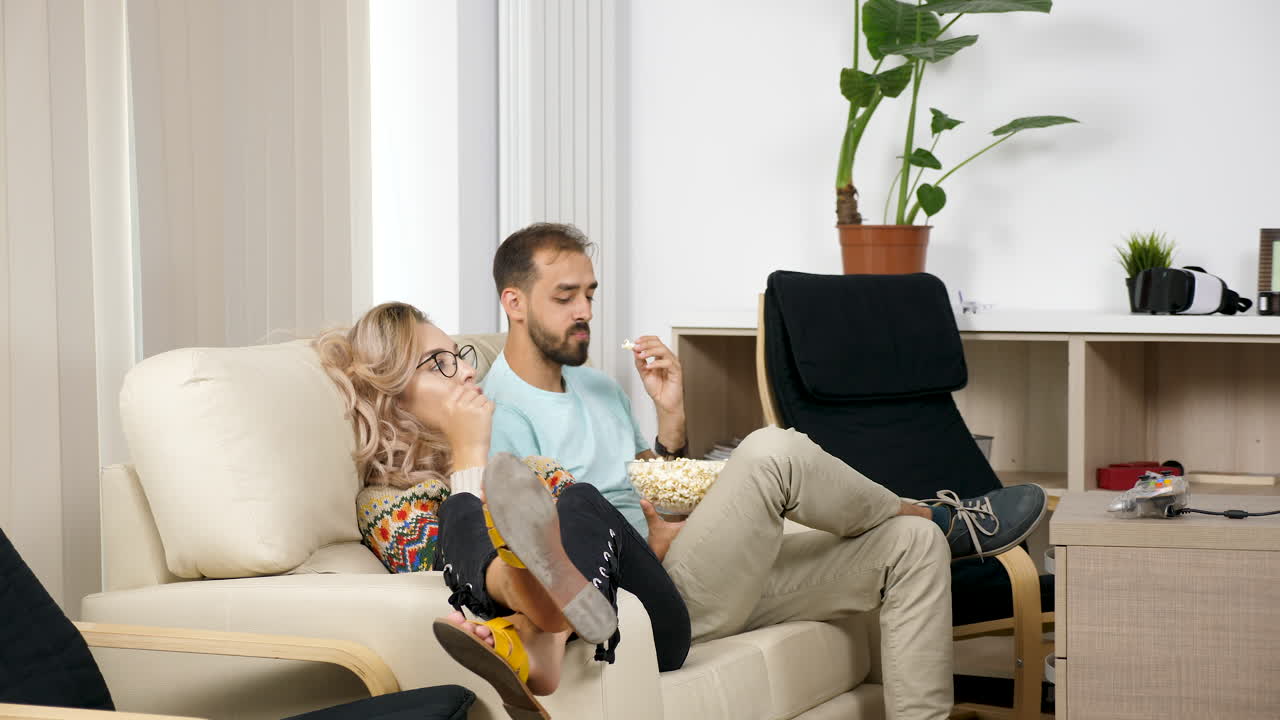 Couple watching TV with popcorn in the living room