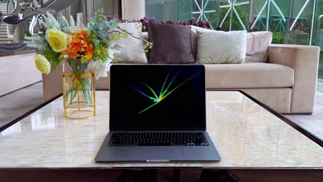 macbook on marble table displaying flurry screensaver inside a luxurious home