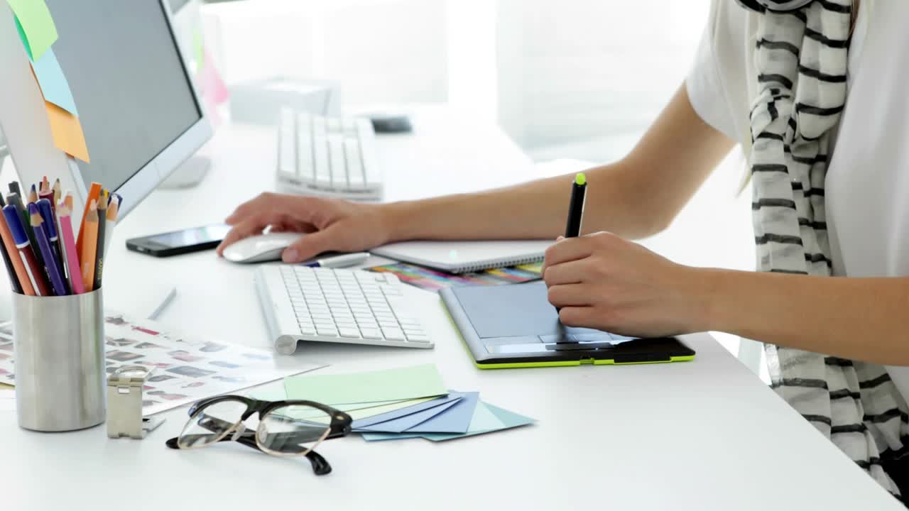 Designer switching mouse and stylus on desk, animating blue network icons while reviewing design