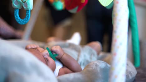 likeable newborn baby girl laying down in cradle with soother dummy nipple in mouth