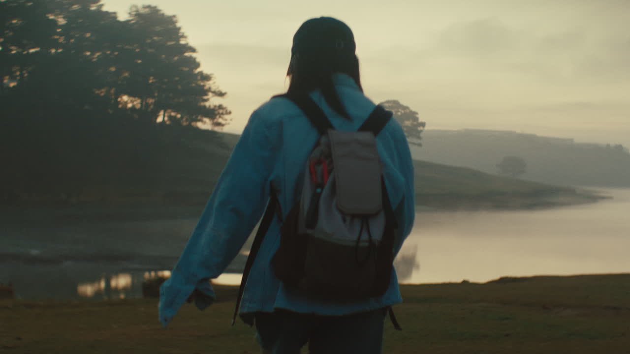 mujer caminando en las montañas brumosas al amanecer
