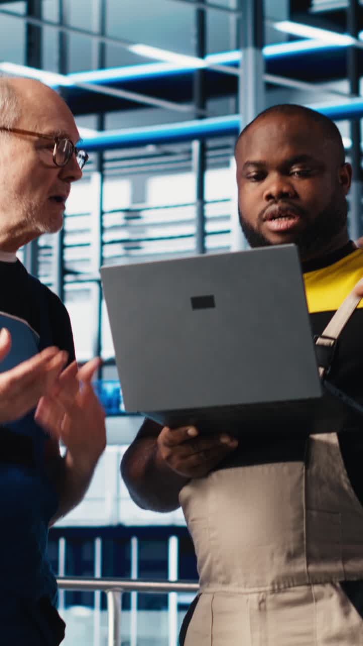 Vertical video Smart factory senior engineer teaches intern to implement automated workflows