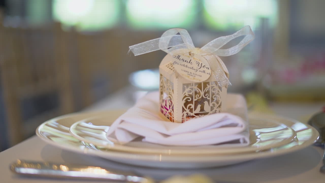 A small gift on the wedding dinner placed in a plate at the dinning table