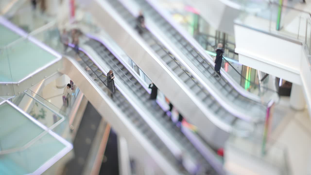 People in motion in escalators at the modern shopping mall. Tilt shift lens shooting with super shallow depth of field.