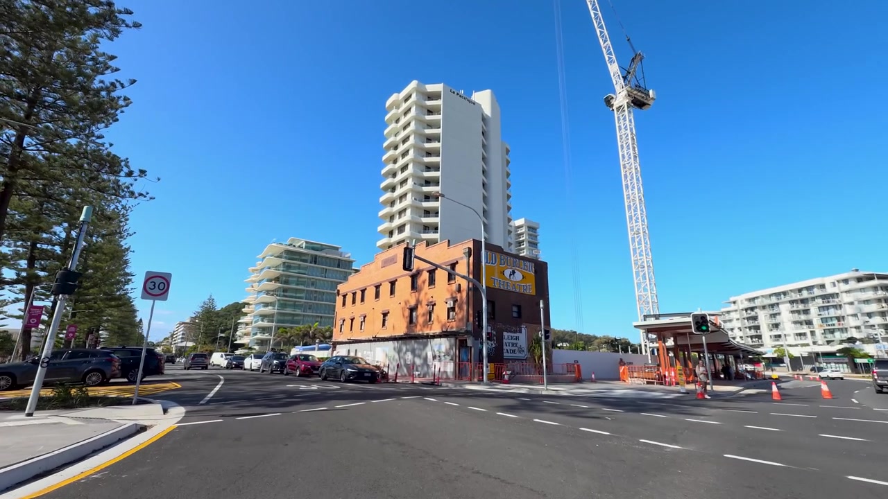 Inquadratura grandangolare in movimento del traffico stradale urbano, di appartamenti moderni e di cieli blu sereni.