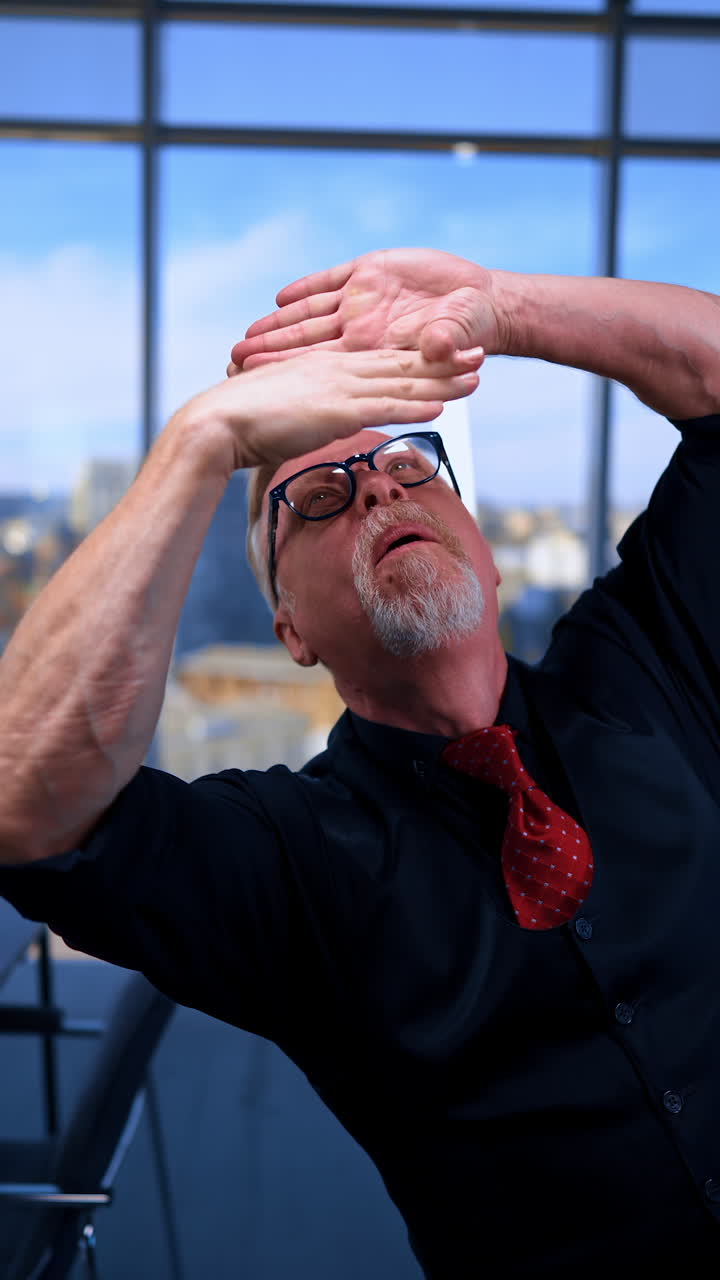 Man wearing shirt and vest looks up. Man puts finger around his eye as if peeping through the binoculars. Vertical video.