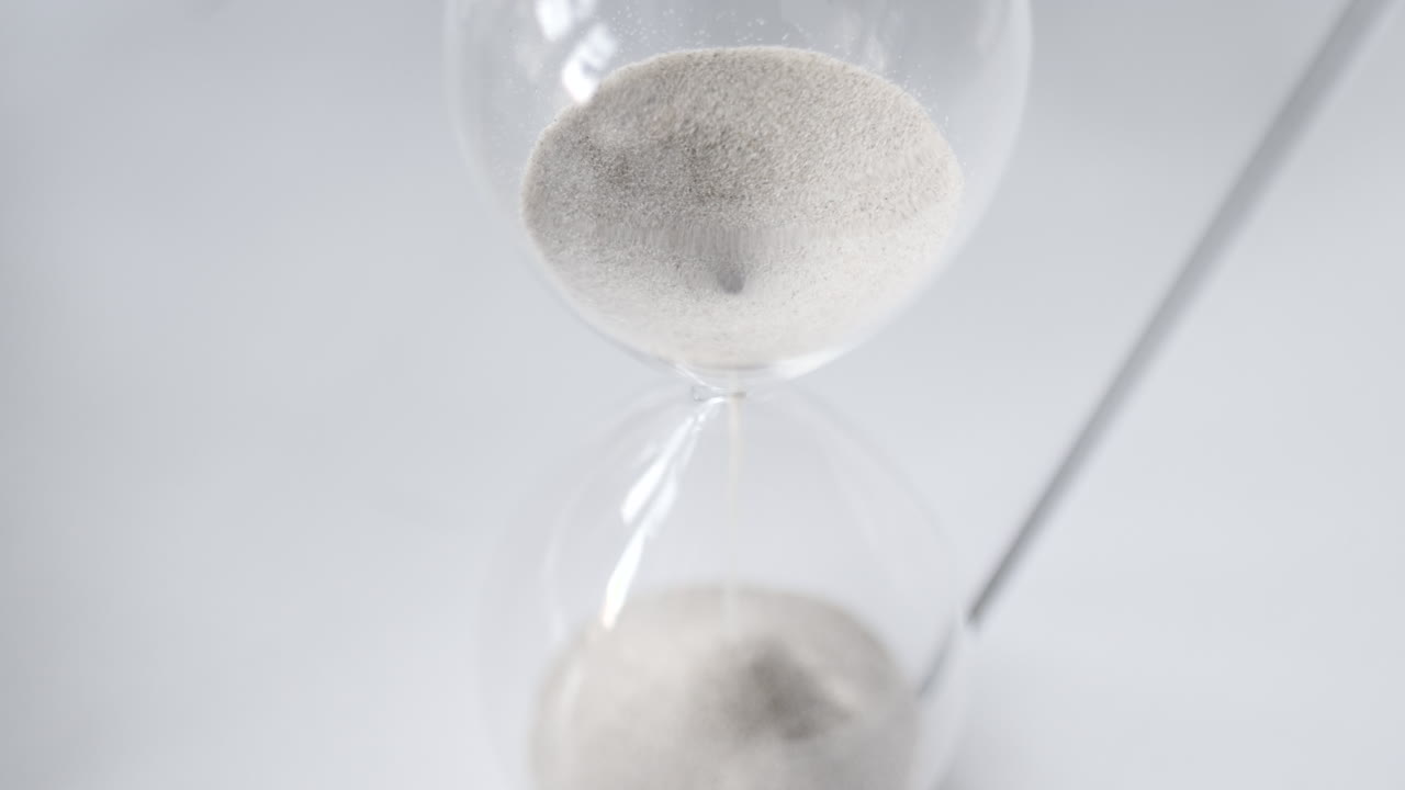 Hourglass sand falling in slow motion from above