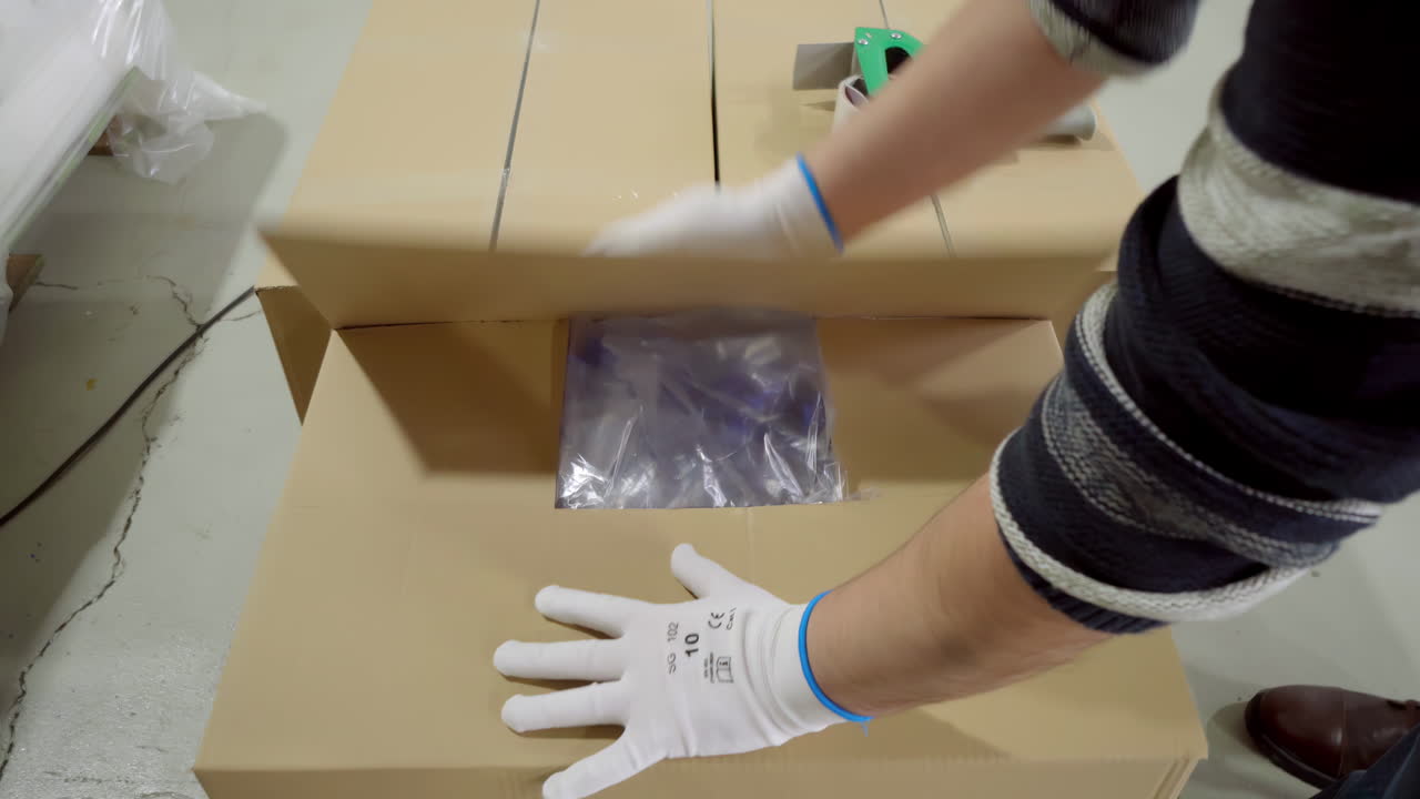 una persona que coloca un producto en una caja de embalaje en un entorno de fábrica - de cerca