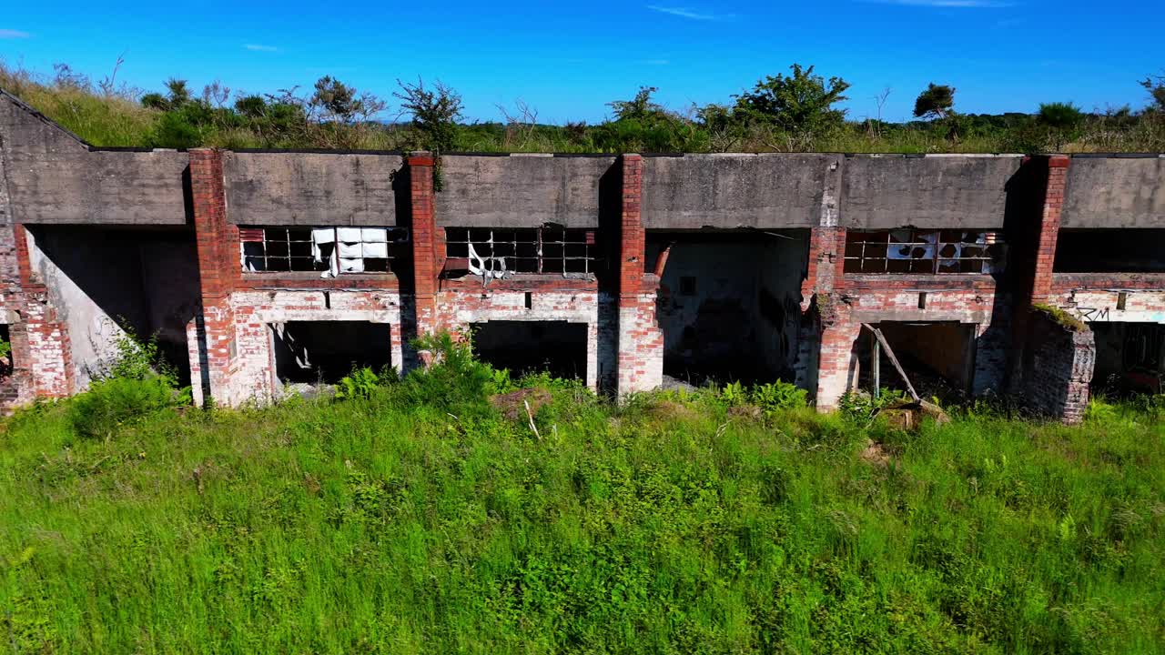 Aerial panning view of abandoned and decaying industrial workshops hidden by overgrown greenery
