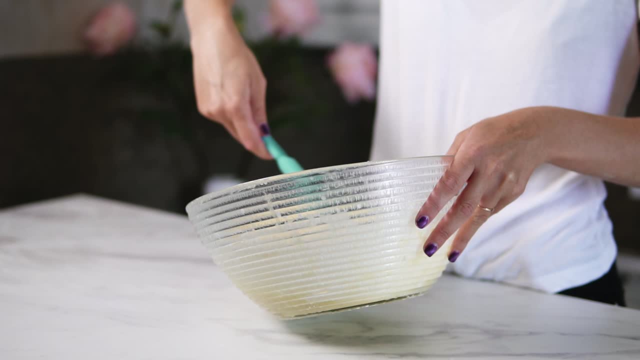 Close Up view of woman's hands mixing ingredients to prepare dough in the the bowl using whisk. Home cooking. Slow Motion shot