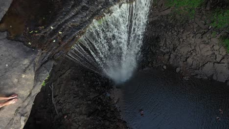 High-Angle-Aerial-View-of-Ozone-Fall,-Natural-Pool-and-Female-Sitting-on-Cliff-Top