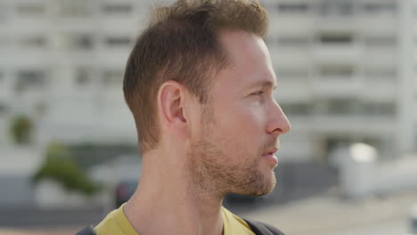 close up portrait handsome young man looking serious turns head pensive caucasian male distracted in sunny urban city