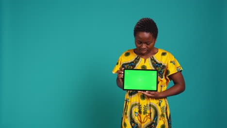 Cheerful-positive-girl-presenting-a-green-screen-on-her-tablet