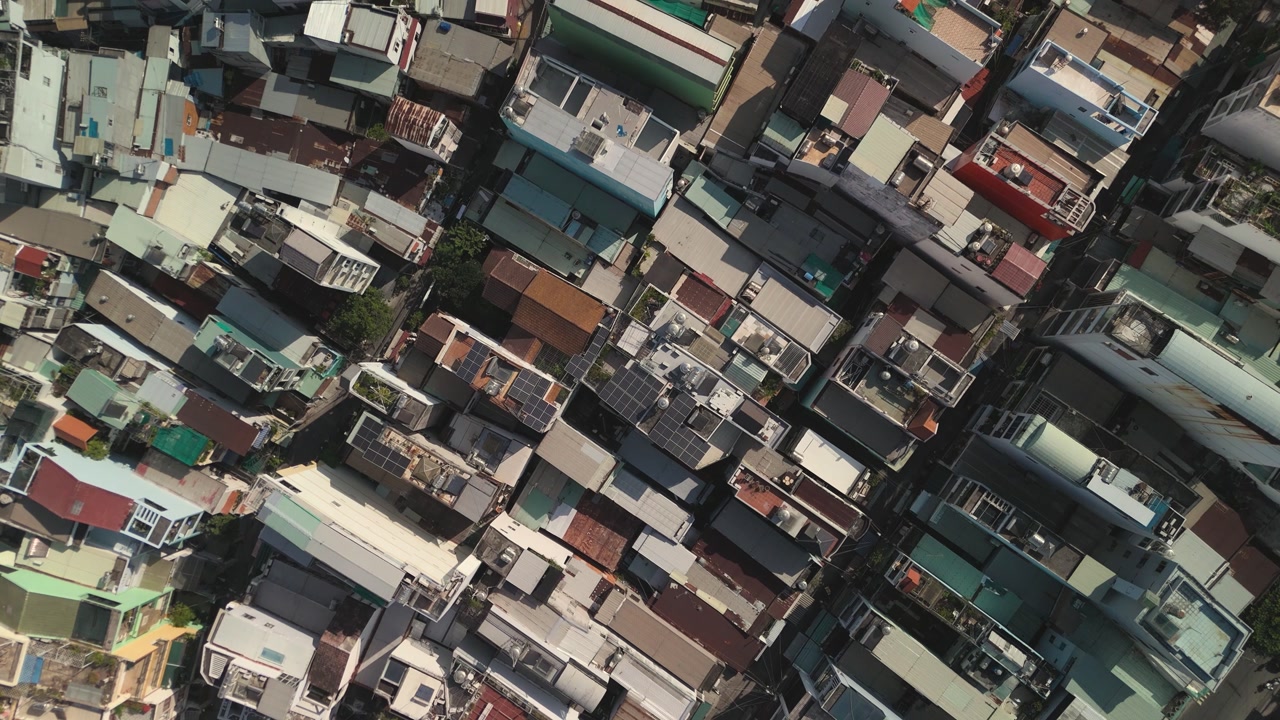 Hi density, crowded area of Southeast Asian developing city on sunny day from top down aerial view.