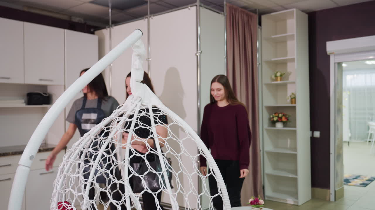 Grupo relajado disfrutando de una silla colgante, reunión llena de risas alrededor de una silla colgante decorativa, amigos relajados en un salón chic con una silla colgante divertida y un ambiente animado