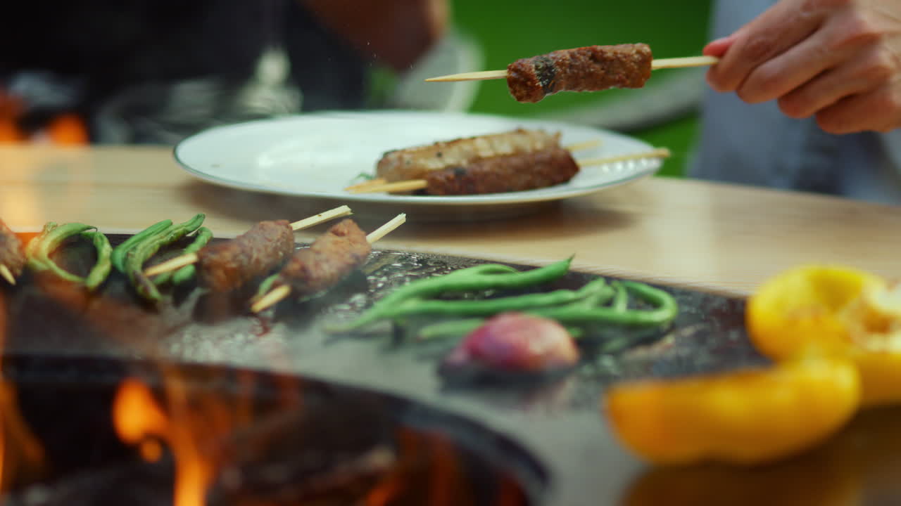Amici che mangiano cibo al barbecue all'aperto. Uomo e donna che prendono il cibo dal barbecue.