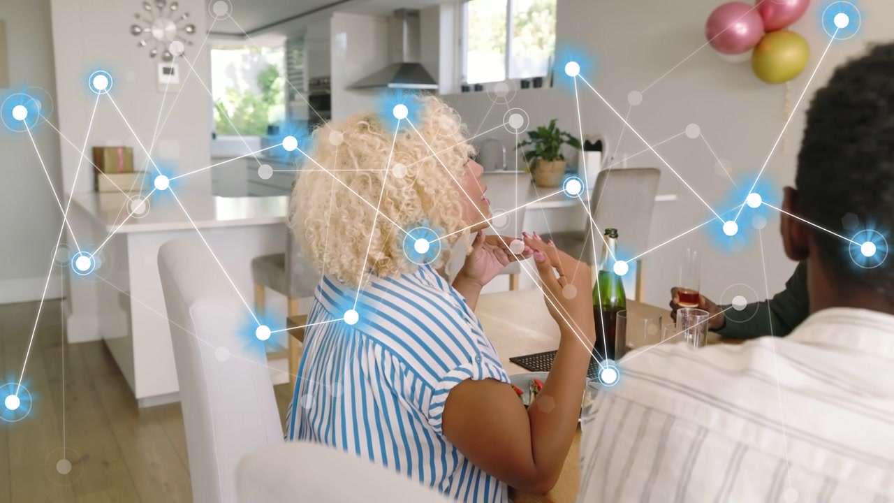 Donna riccia che applaude mentre la telecamera esegue una panoramica, con un overlay di rete che cresce sopra il tavolo da pranzo, mostrando tecnologia.