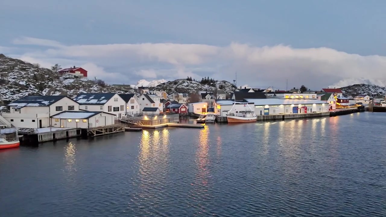 Naturskjønn kystlandsby på Lofoten med fargerike hus og snødekte fjell.