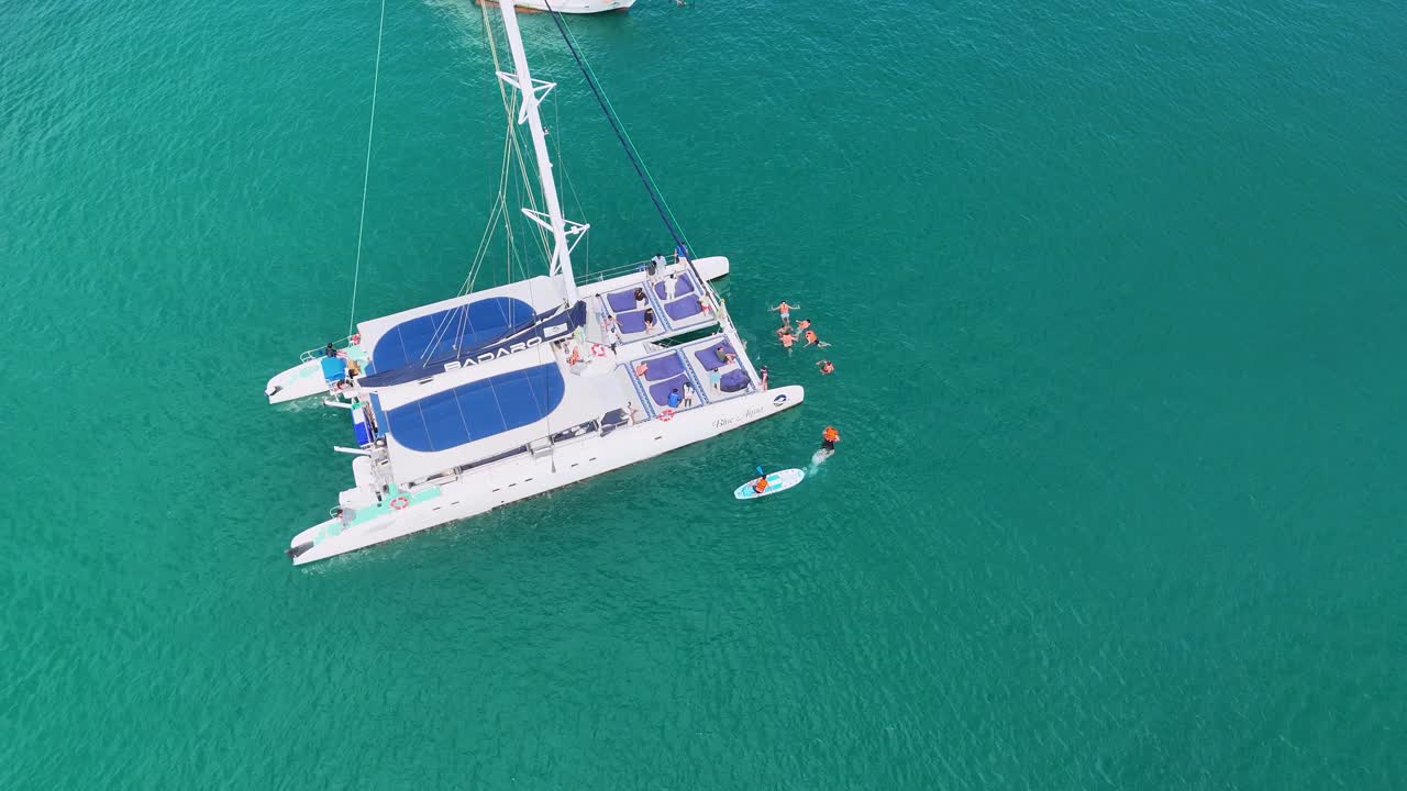 vista aérea de un catamarán con personas nadando cerca en el mar turquesa de phuket, tailandia, bajo la luz del día brillante