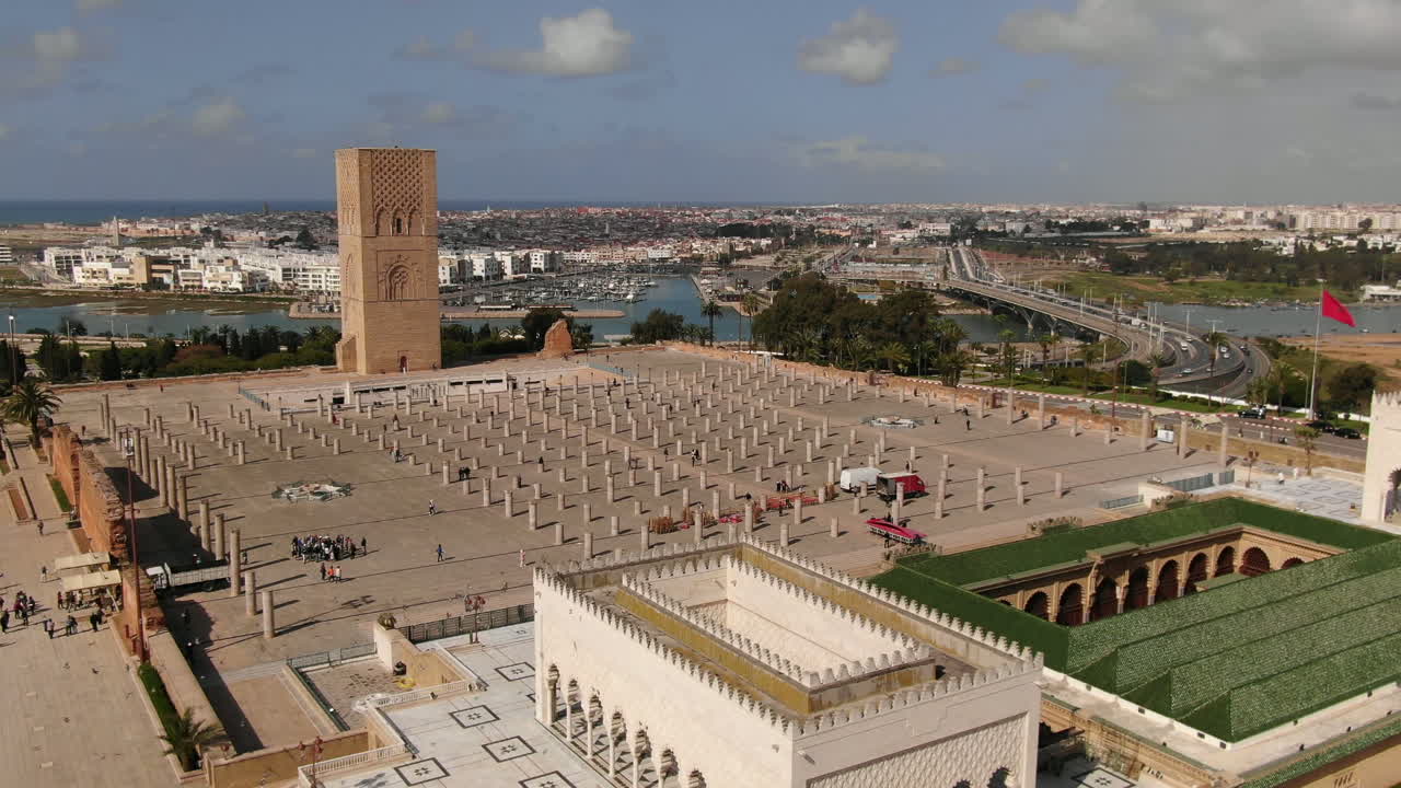 En professionel HD-luftoptagelse fra høj vinkel af Hassan Tower-pladsen i Rabat, Marokko. Optagelsen viser de geometriske rækker af gamle søjler og den ikoniske minaret, med Bou Regreg-floden og
