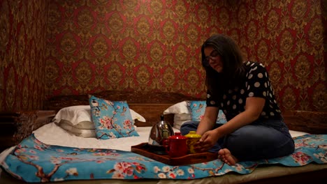 woman holds a ceramic mug to warm up, sitting on colorful chinese kang bed room