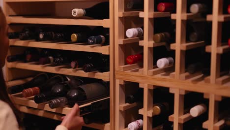 a woman browses a wine rack in a dimly lit cellar, carefully choosing a bottle