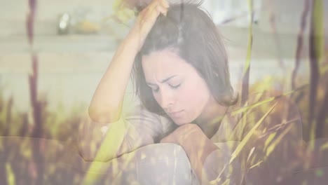 composite video of stressed caucasian woman against tall grass moving in the wind