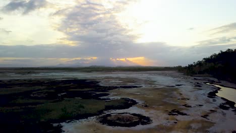 Drone-rises-straight-up-revealing-large-open-salt-pans-and-mud-flats-and-the-saltwater-Bohle-River-in-Townsville,-Australia